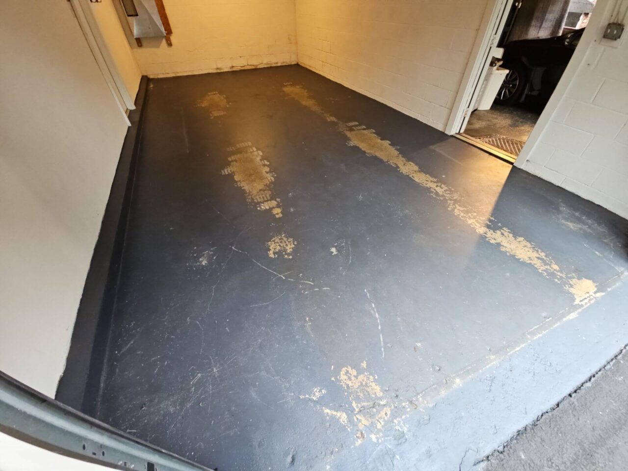 Peeling and worn black paint on a garage floor in Tysons, VA