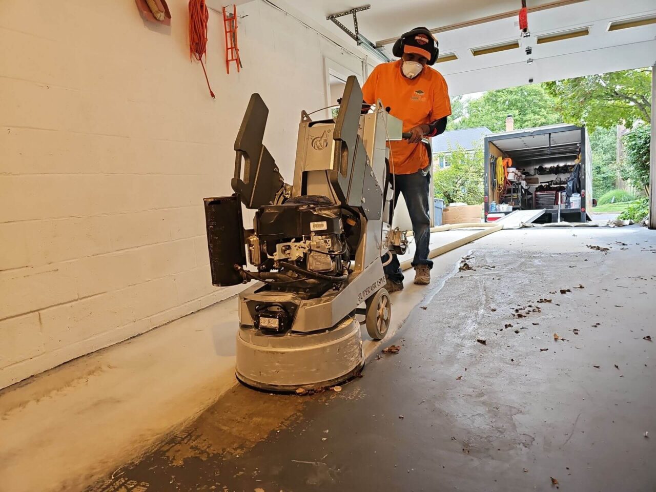 FloorTech crew member using an industrial grinder to remove old paint from the garage floo