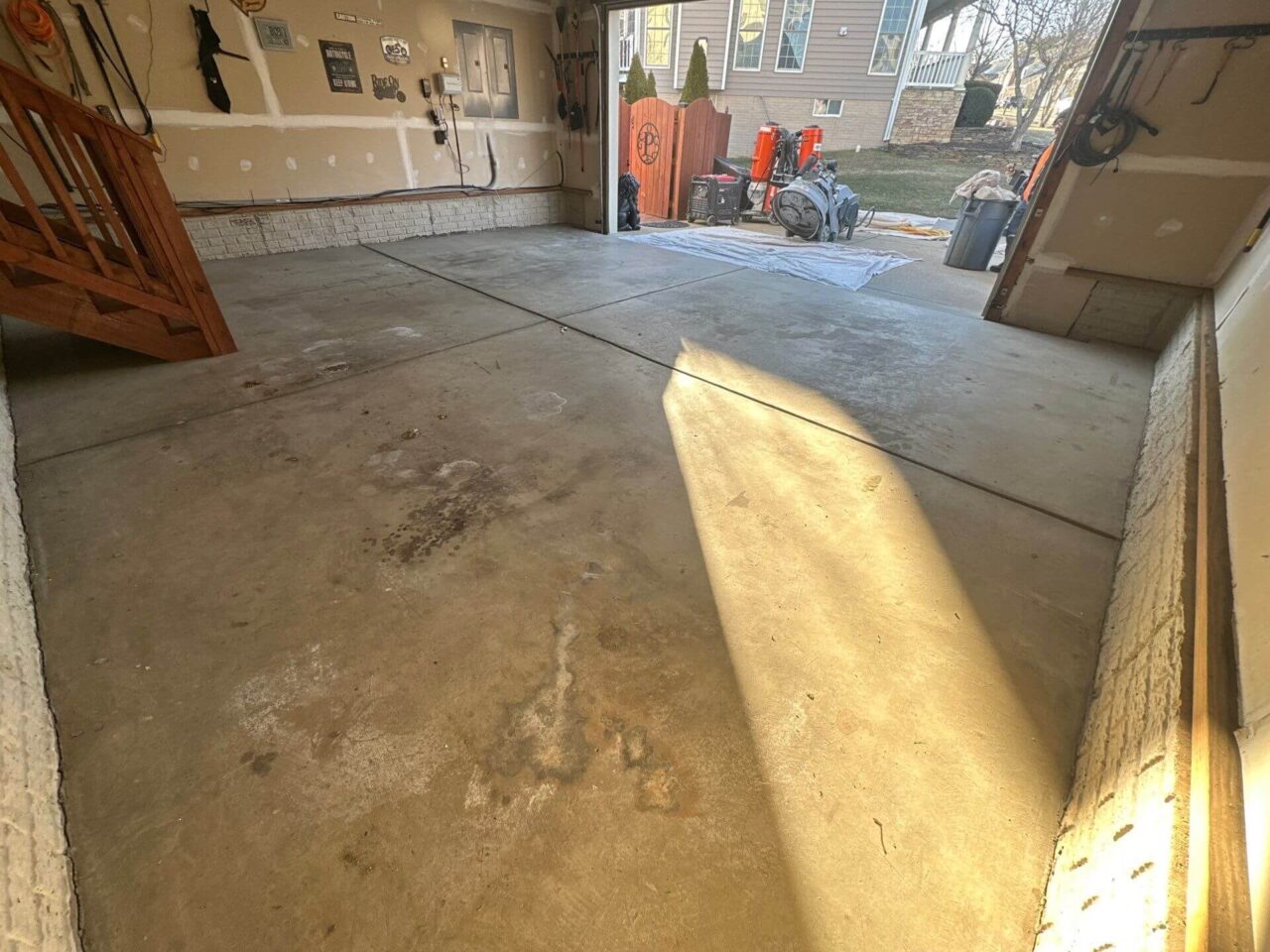 Uncoated garage floor with visible oil stains and discoloration near the entry.