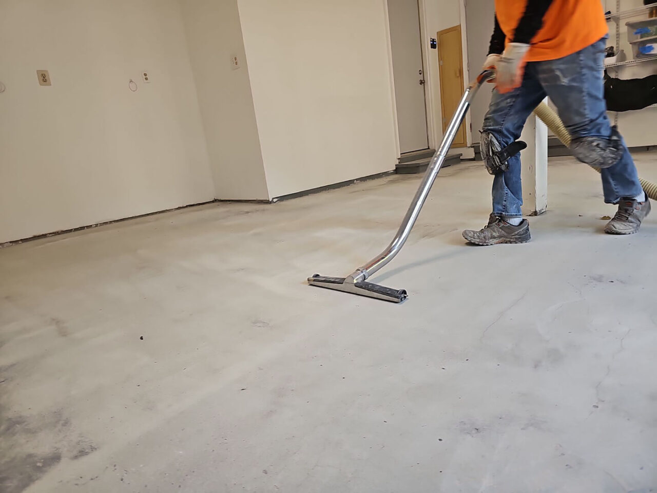 FloorTech technician vacuuming concrete dust during surface preparation.