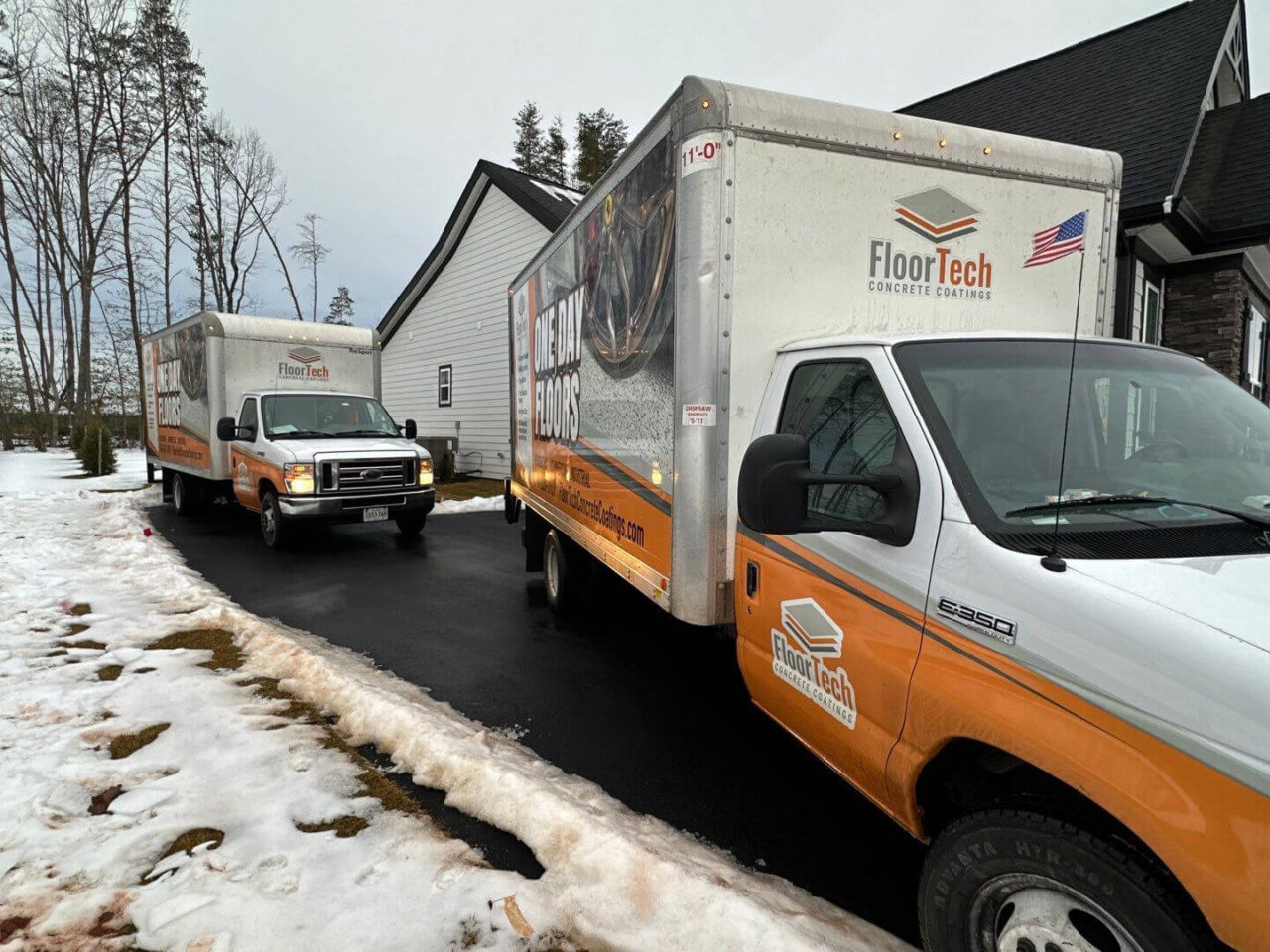 Two FloorTech box trucks parked in front of home during a snowy winter install.
