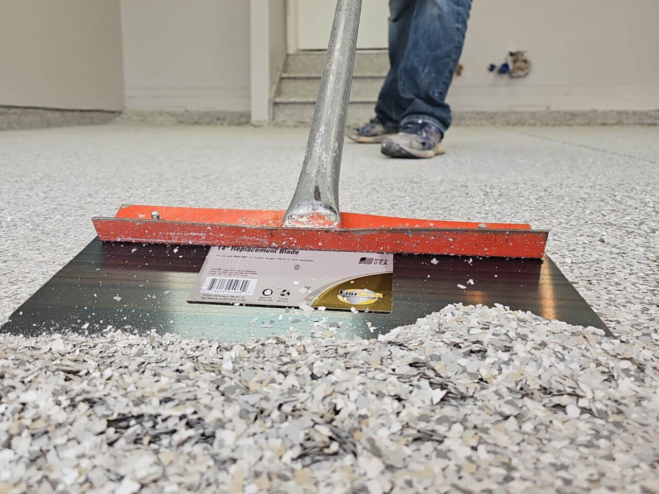 Installer broadcasting Mount Everest flake across garage floor surface.
