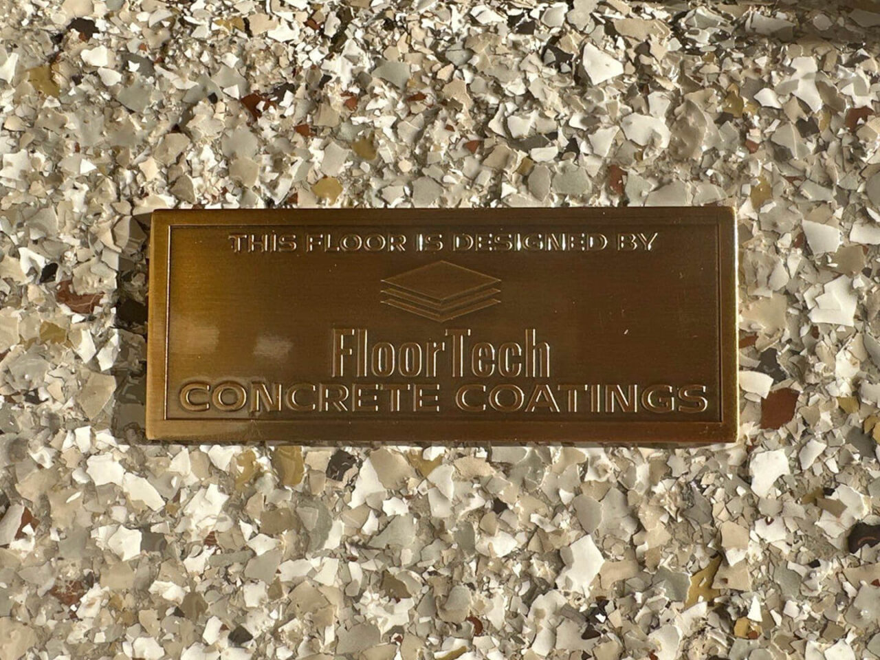 Gold FloorTech badge placed on the finished Pebble Beach flake surface.