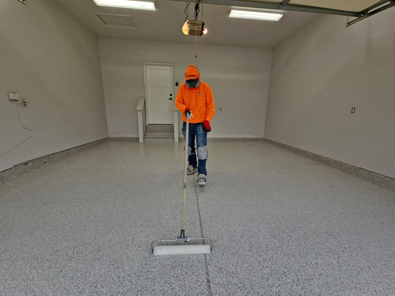 Polyaspartic topcoat being rolled out to seal flake system.