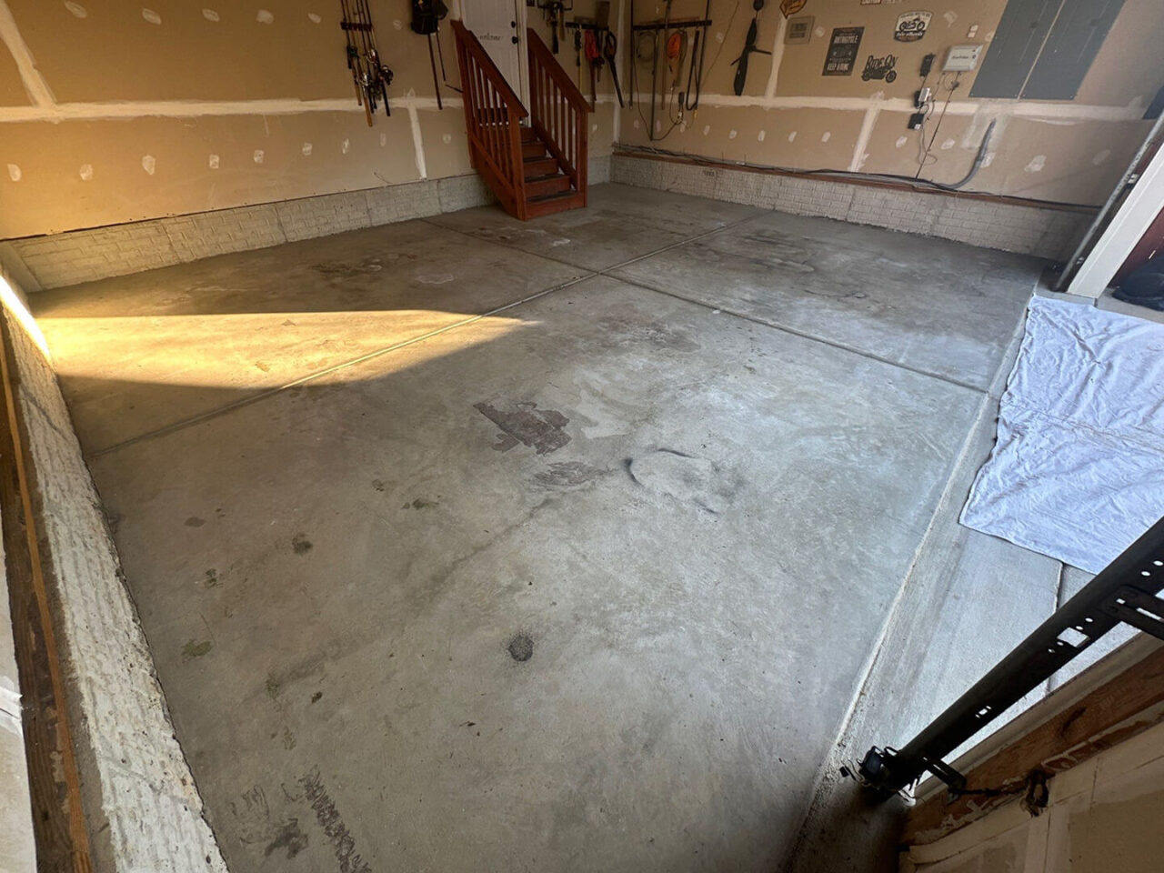 Wider view of bare concrete floor showing wear and embedded tire marks.