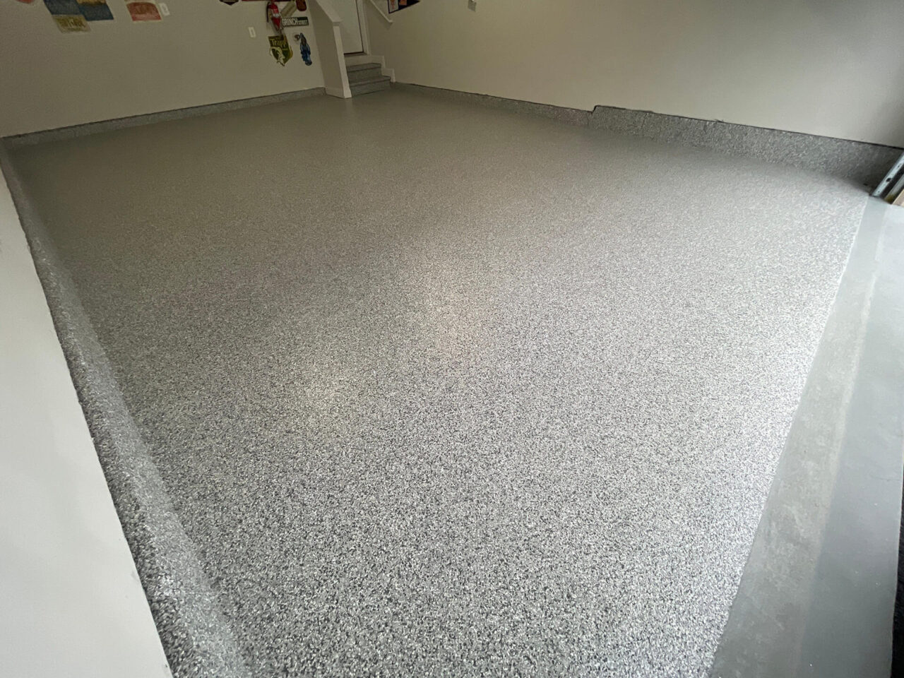 Wide view of the garage floor fully coated in slate stone flake, including cove base and entry steps.