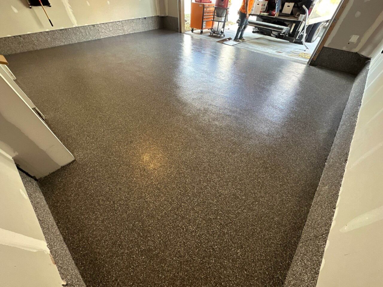 Garage view from corner showing coated floor, stem walls, and visible FloorTech crew
