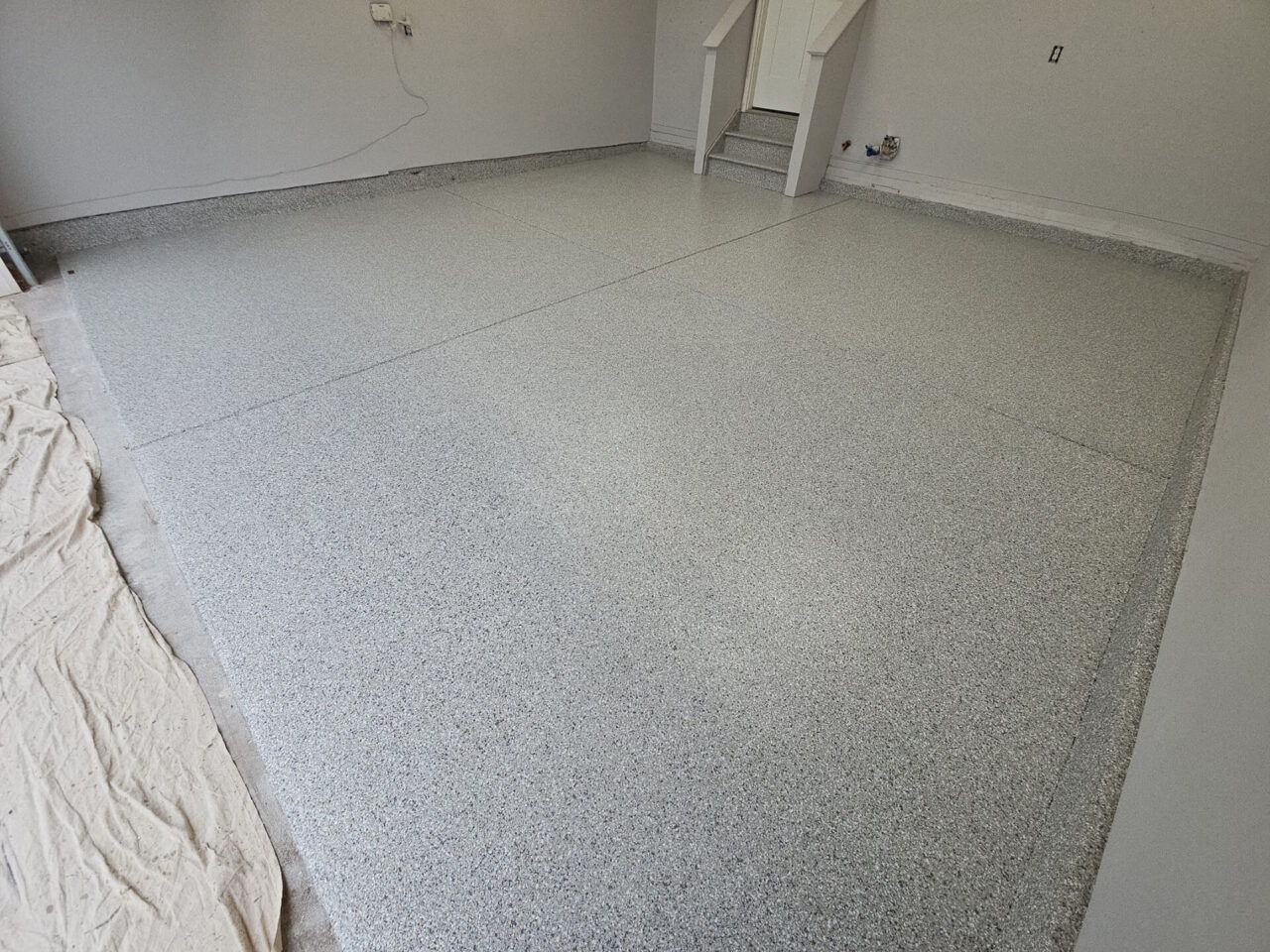Corner view of coated garage floor with crisp stem wall finish and clean transitions.