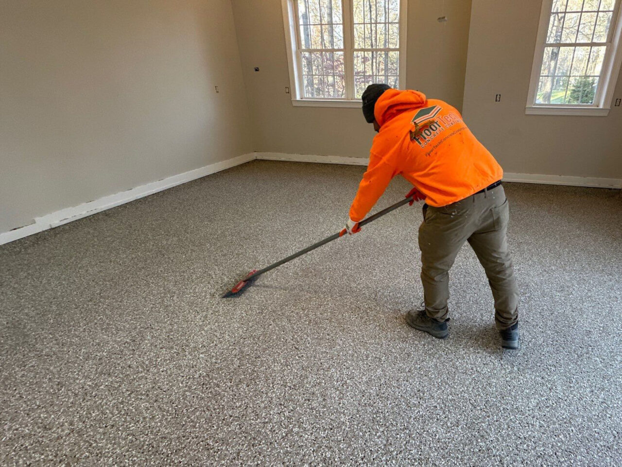 FloorTech installer backrolling polyaspartic topcoat across newly coated garage floor.