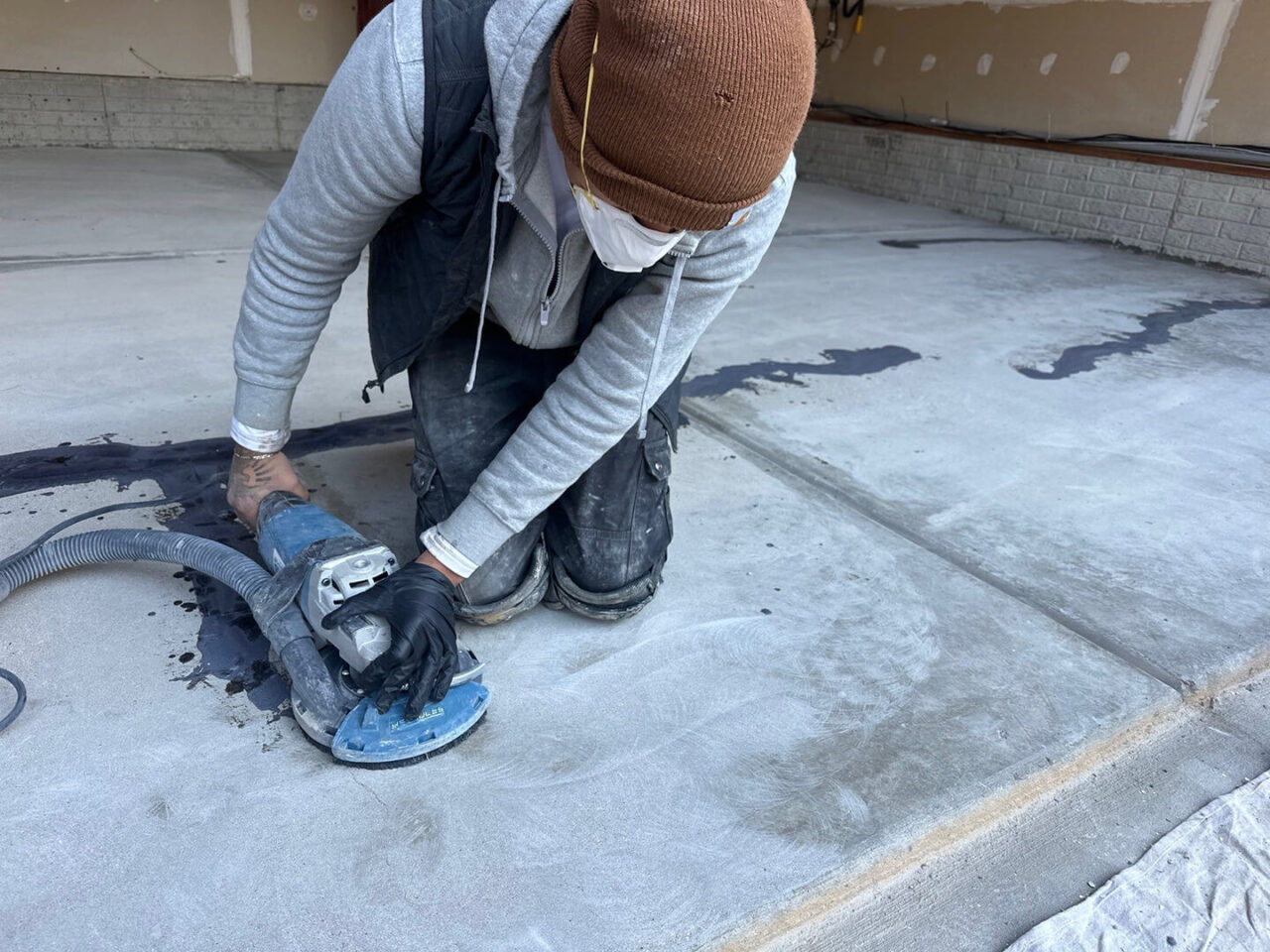Technician grinding edges of garage floor for even coating adhesion.