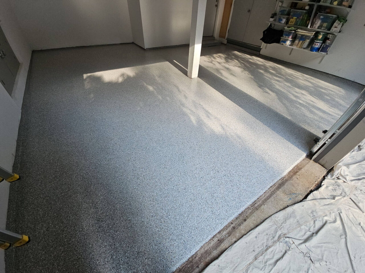 View from garage entrance showing a smooth Mount Everest flake floor with sunlight casting natural shadows.