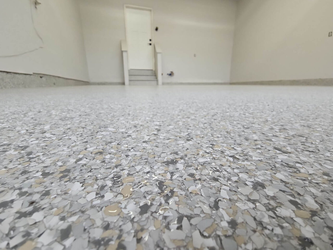 Two-car garage with freshly coated floor, clean trim lines, and coated stairs visible.