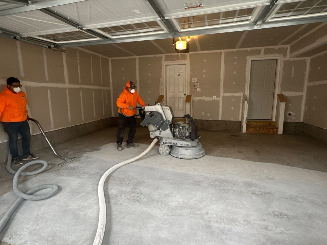 Concrete grinding in progress with two FloorTech crew members using dust-controlled machinery