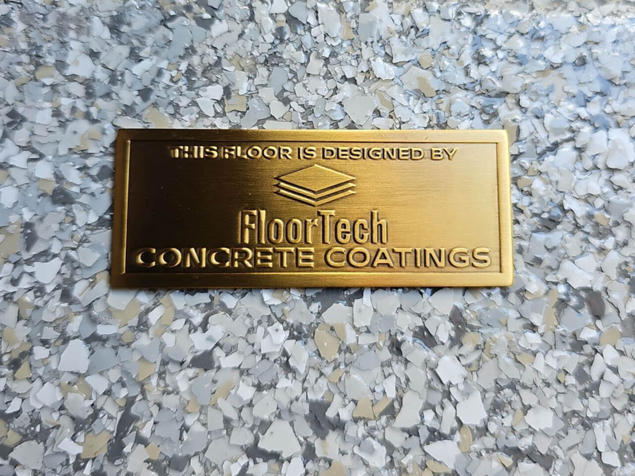 Close-up of FloorTech’s signature badge placed on the finished Mount Everest garage floor.