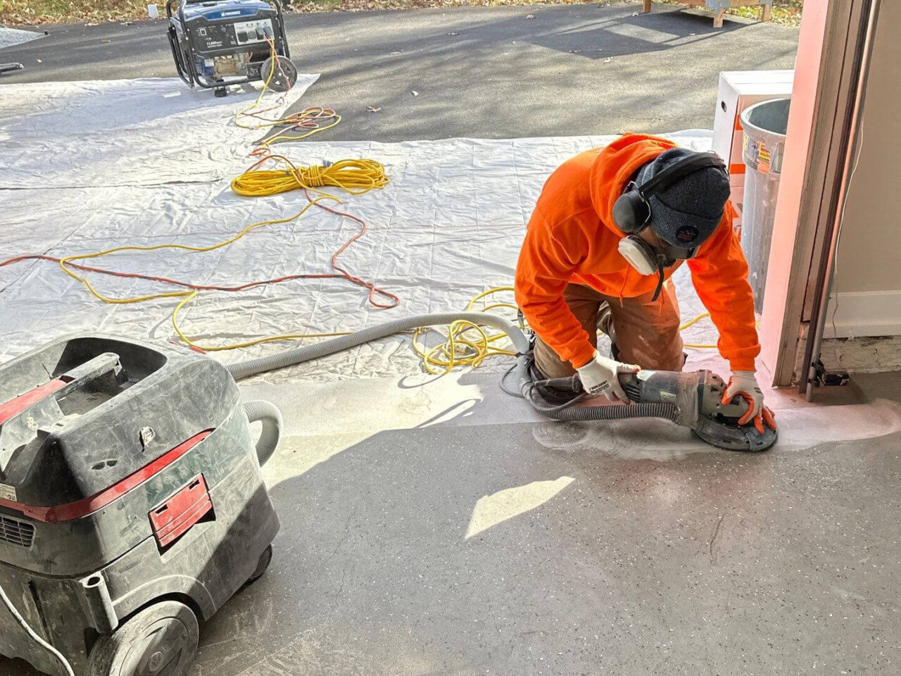 Installer using a hand grinder to prep garage edges for flake coating application.