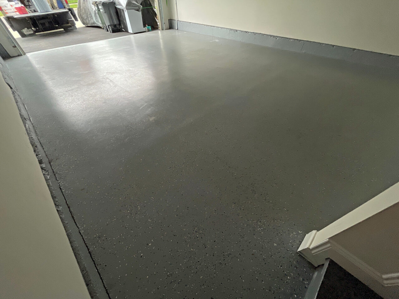 Before photo showing old DIY gray floor coating with patchy wear and visible discoloration.