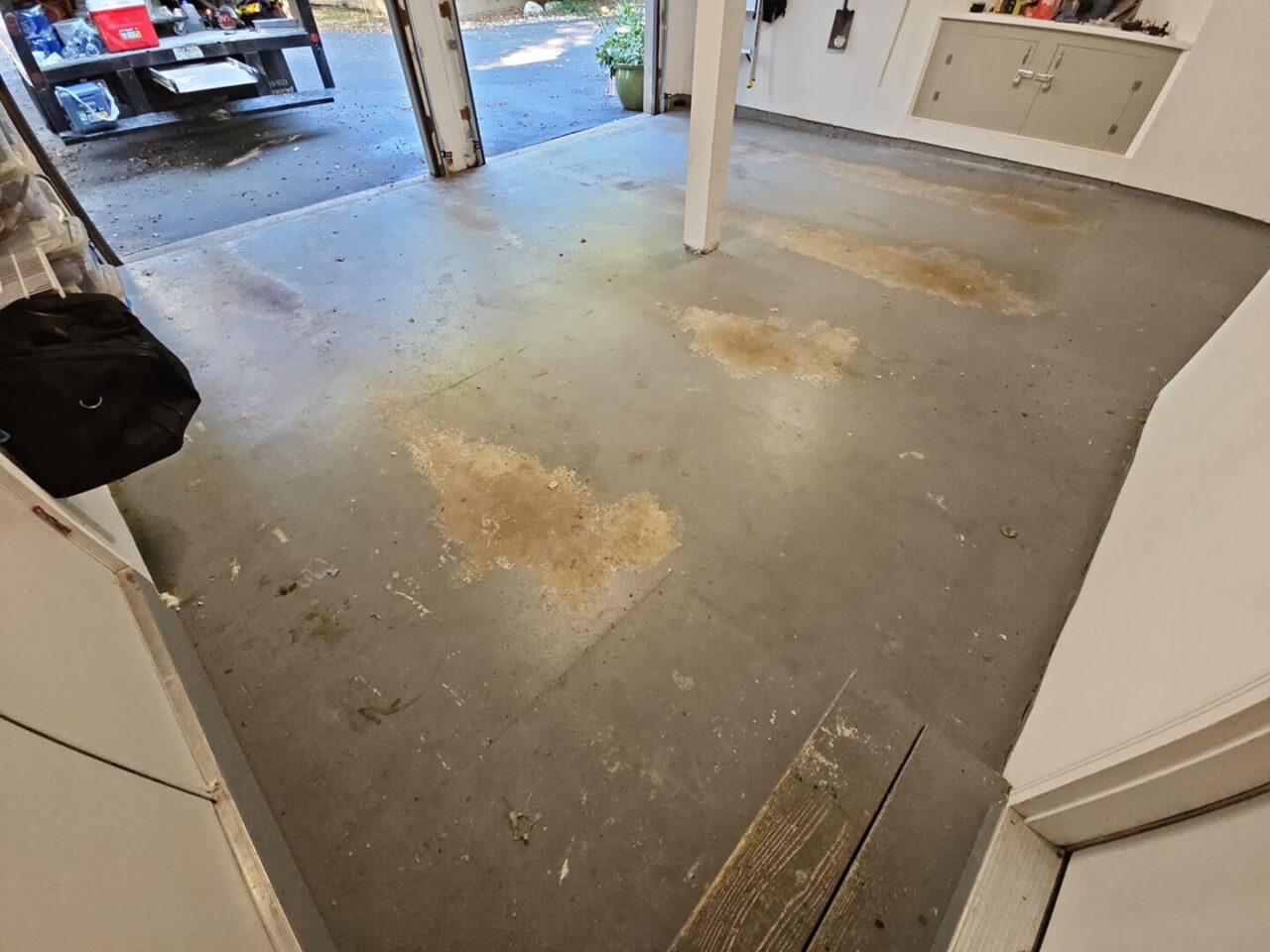 Worn and stained painted garage floor with hot tire pickup marks and heavy discoloration before coating.