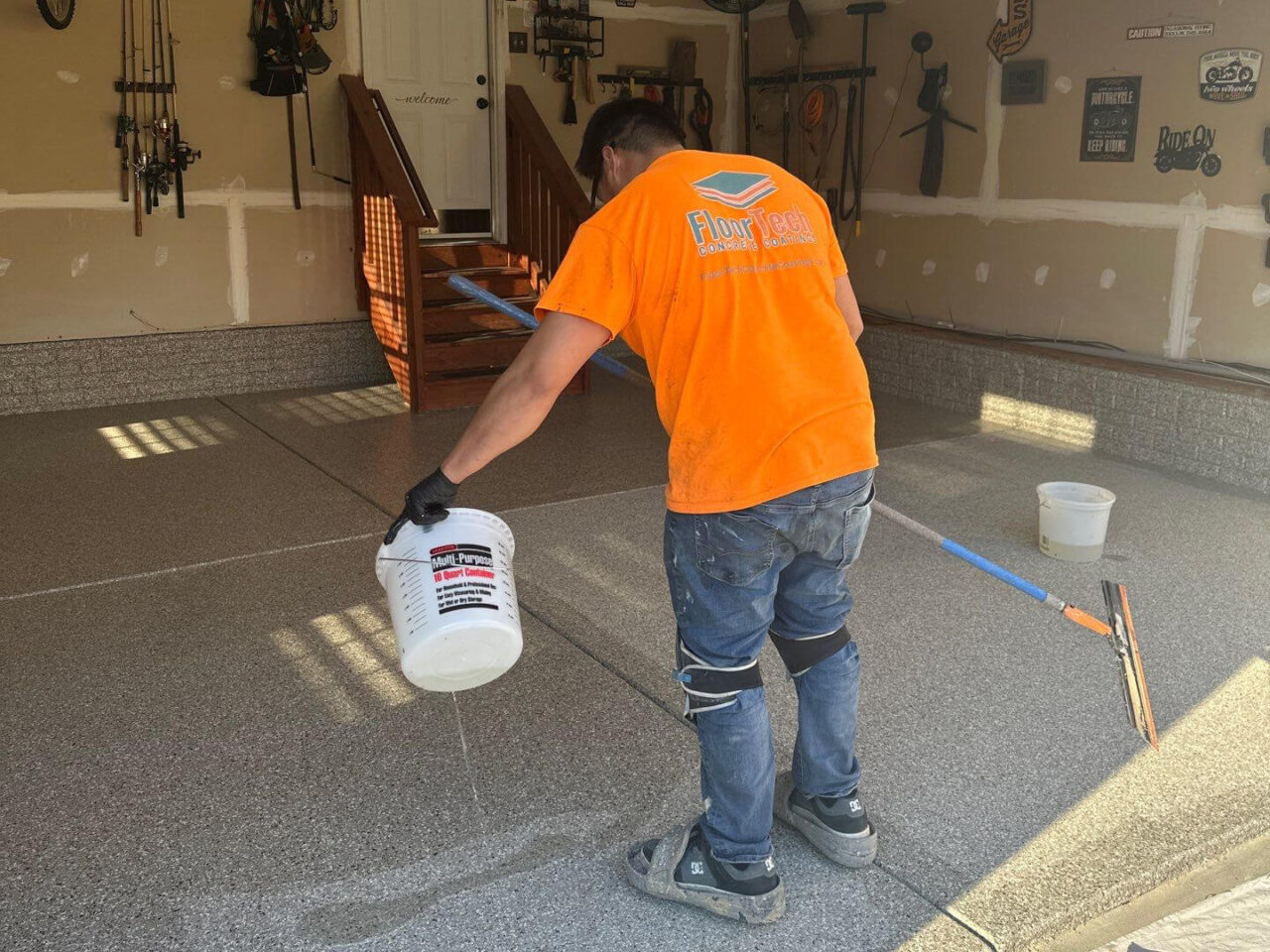 Topcoat application in progress on flaked floor surface.