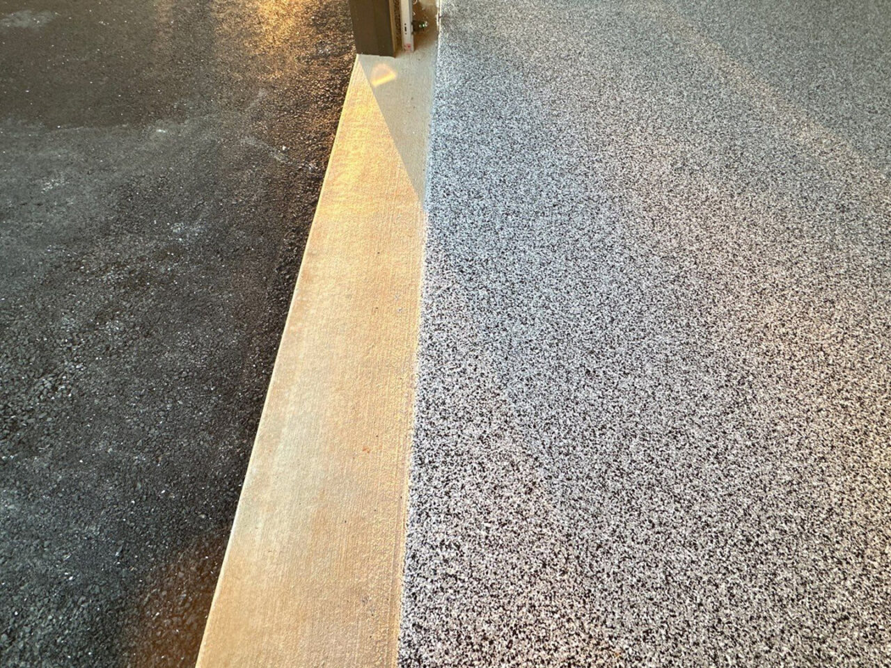 Garage threshold and entry point where coated floor meets asphalt driveway.