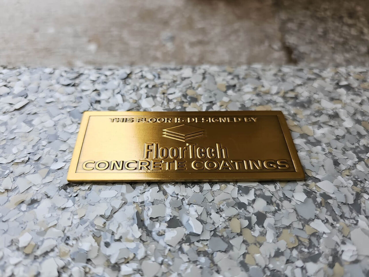 FloorTech badge placed at garage entrance on finished flake floor.