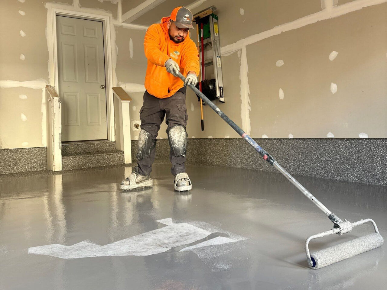 Base coat being applied with roller across prepped concrete floor