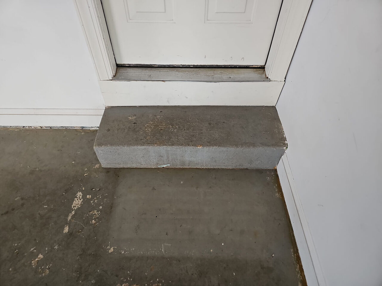 Uncoated concrete step at garage entry door