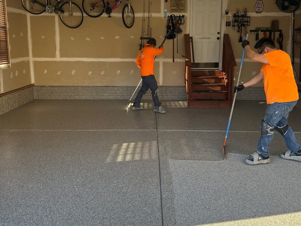 Two installers spreading topcoat to seal the flake system.