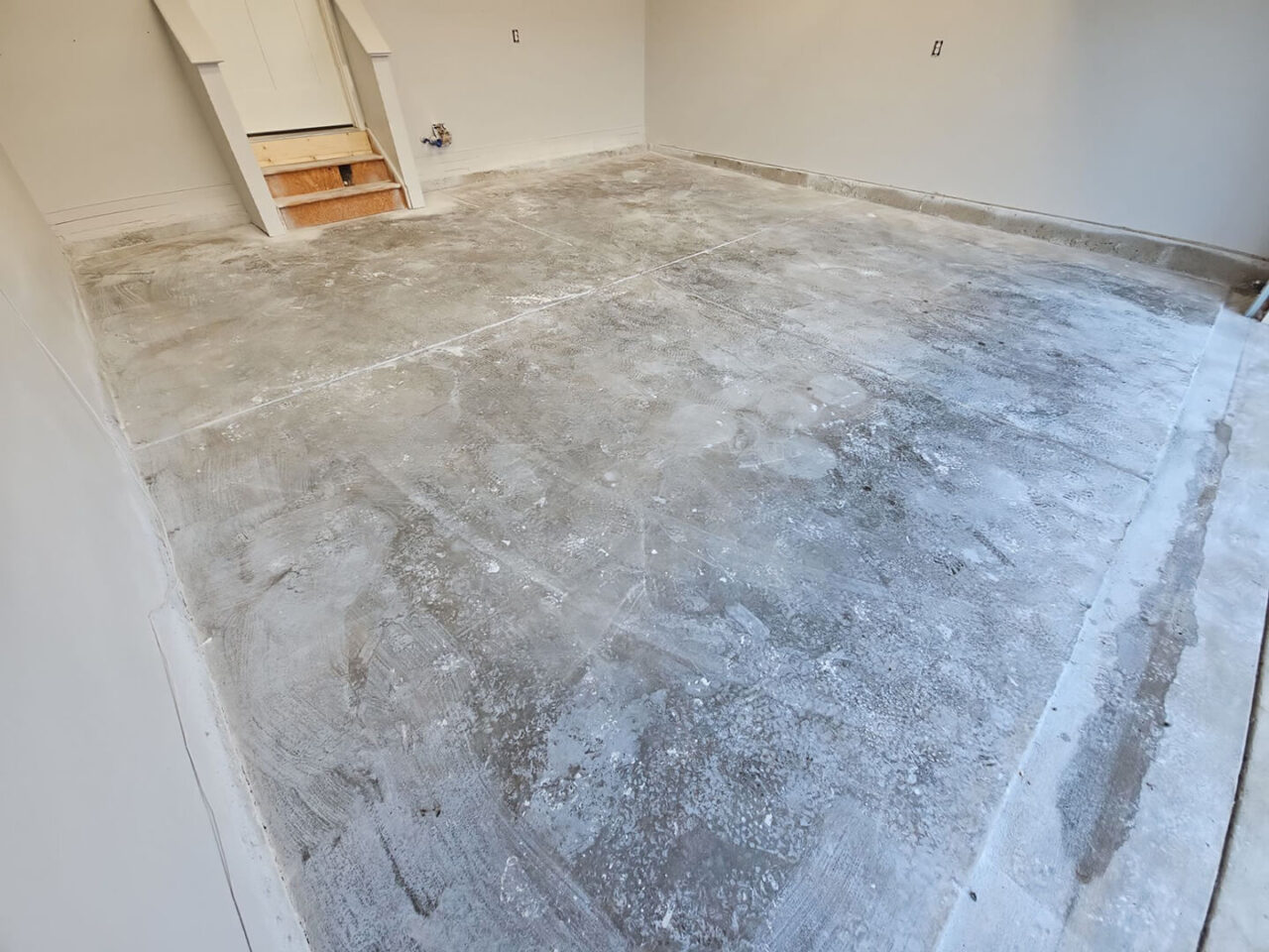 Bare concrete garage floor showing discoloration and minor residue near walls.