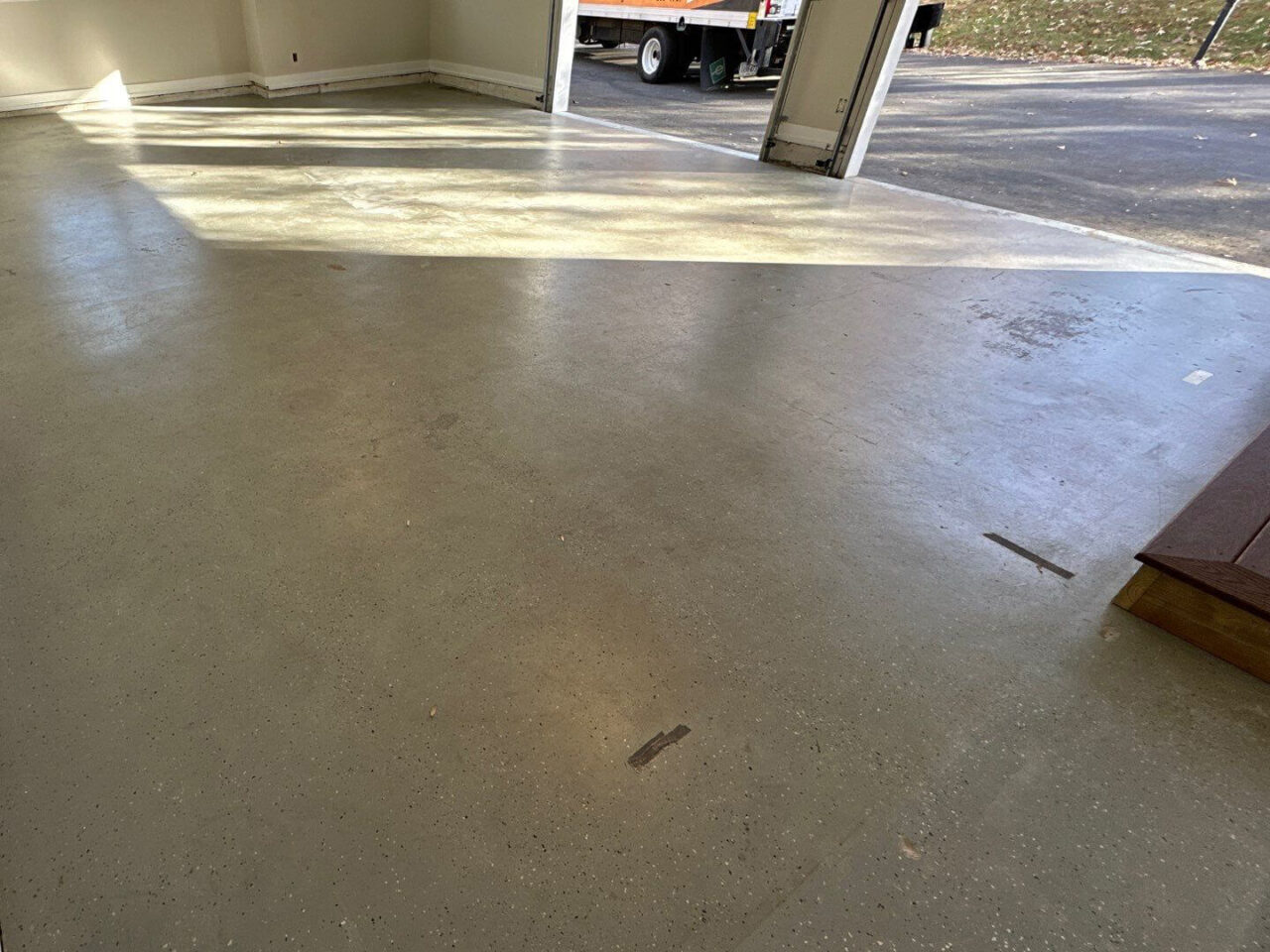 Bare concrete garage floor before coating showing previous worn paint and discoloration.