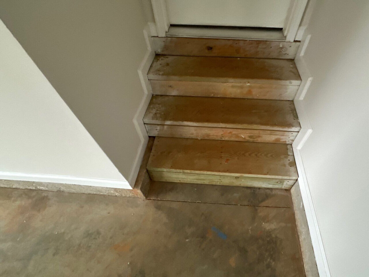 Uncoated garage floor with worn, discolored concrete surface.
