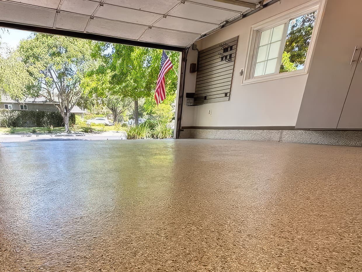 A tan polyurea garage floor coating in a Virginia home, showing the smooth full-broadcast finish used in FloorTech’s engineered coating system.